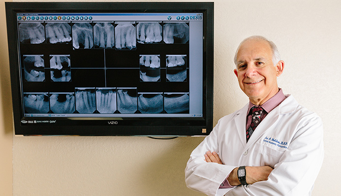 Dr. Lee Sheldon in front of dental X-rays