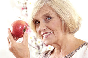 older woman holding apple smiles