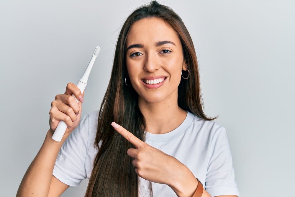 young woman holds electric toothbrush