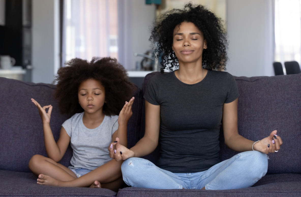 woman and girl meditating on couch