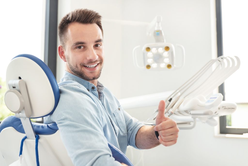Happy patient giving thumbs up in dental chair