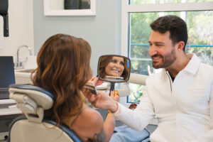 woman smiling in the mirror at the dentist
