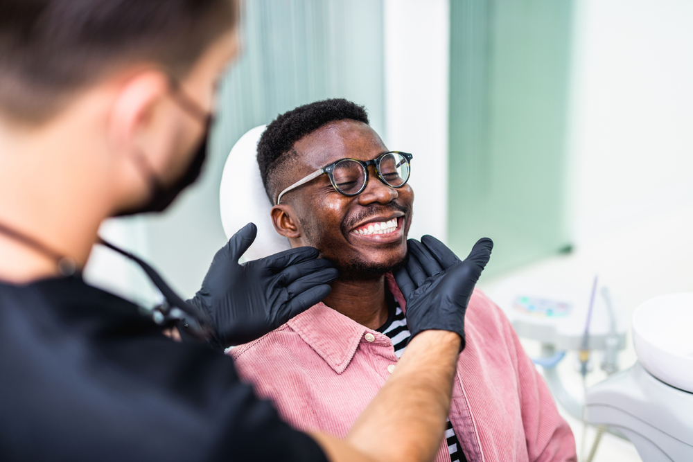 dentist wearing black gloves checks mans' smile