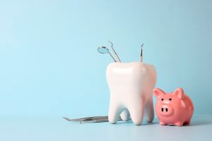 piggy bank next to model tooth and dental tools